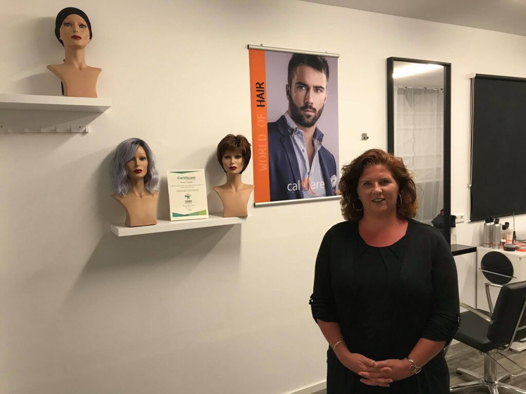Wendy in haar salon, met haarwerken op de plank